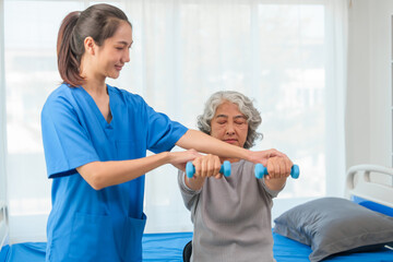 A young Asian nurse is assisting an elderly Asian woman with a grey hair during a physical therapy session.