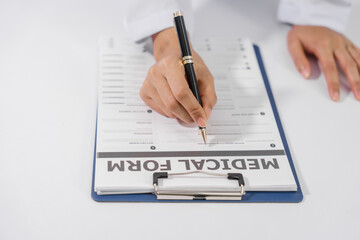 Close-up of a doctor hand holding pen and writing on medical form that attached to a clipboard.