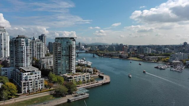 Drone shot of the Sea Wall in Yaletown downtown Vancouver including False Creek, buildings, boats, trees, bridge during summer.