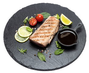 grilled cooked piece of tuna fillet on black stone serving board