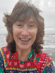 Selfie of a mature woman wearing a colourful rash vest while swimming in the sea on Boxing Day. Swimming in cold or open sea water during the winter months is good for physical and mental health.