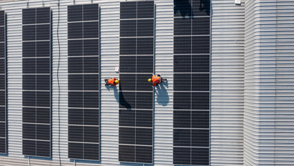 Aerial top view of Engineering technician is a professional trained in skills and techniques installing solar photovoltaic panels system on power industrial factory roof, Engineering concepts. © AU USAnakul