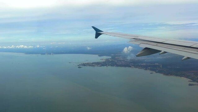 Flying over the Malaysian coastline through airliner window. Crossing the coastline of Malaysia through plane window.
