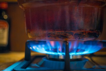 Worn out stove pot or cooking pan on a burning gas hob