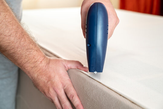 Worker stapling sofa lining with electric staple gun
