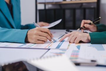 Two professionals are calculating finances, one using a calculator and the other taking notes,...