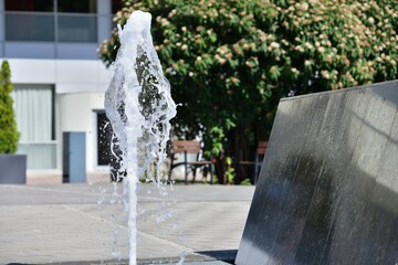 The urban white water fountain sprays up a geyser of water in the summer