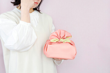 贈り物に悩む女性のイメージ　ピンク背景