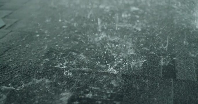 Heavy rain pours on the roof of a house made of soft shingles