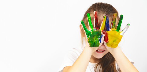 Childish pranks. Child with painted palms with multicolored paints. A little girl happily draws...