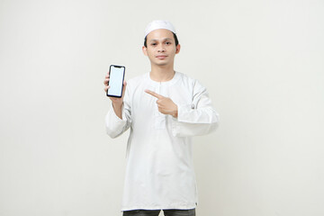 happy asian muslim showing blank phone screen and give pointing finger gesture. People religious Islam lifestyle concept. celebration Ramadan and ied Mubarak. on isolated background.