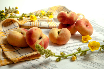 Several whole saturn peaches or flat peach on white wooden background..