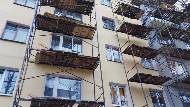 Reconstruction and repair of an old multi-storey building. Scaffolding near a house in the city. Replacement of window frames and balconies, construction