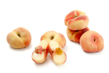 Half and several whole saturn peaches or flat peaches isolated on white background with clipping...