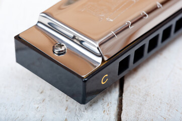 A metal harmonica with ten holes, a wind instrument, photographed on a wooden surface.