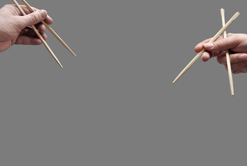 Asian chopsticks held in human hands on monochrome dark pink background. Without food. No...