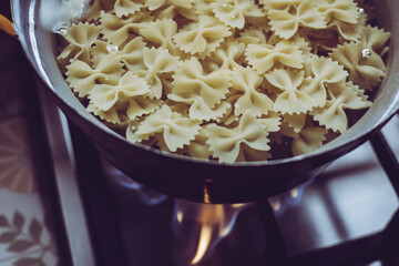 Cooking farfalle pasta on a burning gas hob