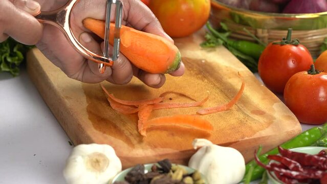 A woman using a vegetable peeler to peel carrots in preparation for roasting for dinner
