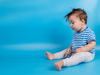 Baby on blue background. The emotions of a child, copy space.