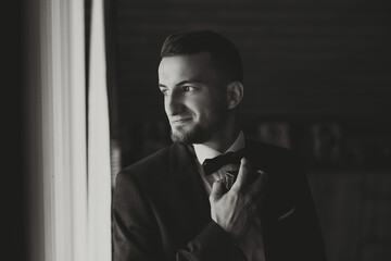 Man spraying luxury perfume on black background, closeup. The image of a man's profile, the man sprays perfume on herself Squirting on the neck. Black and white photo.