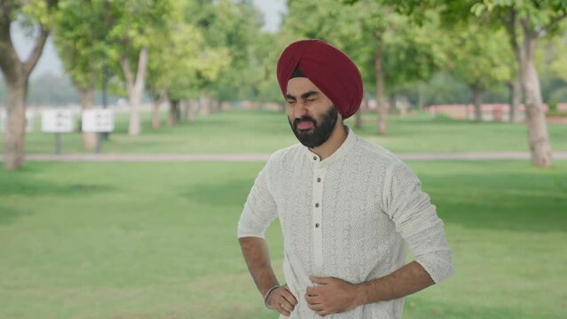 Sick Sikh Indian man suffering from stomach pain in park