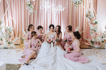 Group portrait of the bride and bridesmaids. Bride in a wedding dress and bridesmaids in pink or...