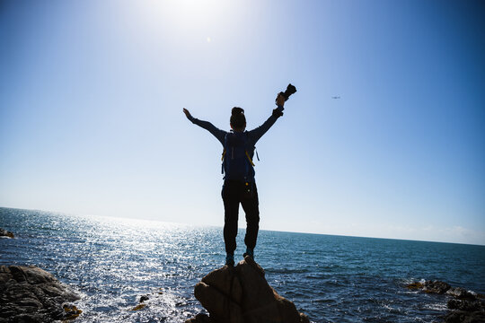 Woman photographer enjoy the view on sunrise seaside rocks - Powered by Adobe