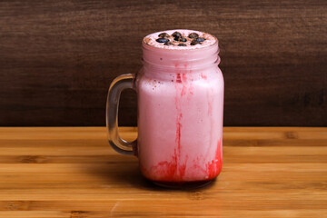 a jar of strawberry and coffee milkshake on a wooden background