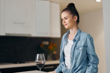 Solitude and Sorrow: A Depressed Young Woman, Sitting Alone in a Stylish Kitchen, Holding a Glass...