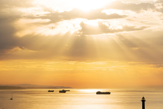 Ships in the roadstead against sun rays from the clouds