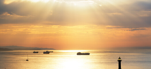 Panoramic view of sunrays above the sea and ships