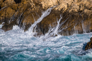 Olas rompiendo contra rocas en el agua del mar