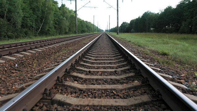 Empty flat straight intercity railway tracks. Transportation and delivery of goods. Public rail transport for passengers. Flying at speed over rails and sleepers, point of view.