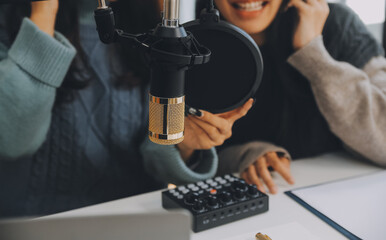 Woman recording a podcast on her laptop computer with headphones and a microscope. Female podcaster making audio podcast from her home studio.