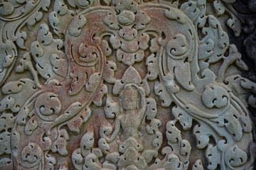 Ancient asian stone wall with human and flower ornaments in Cambodia Angkor Wat Siem Reap for pattern background horizontal