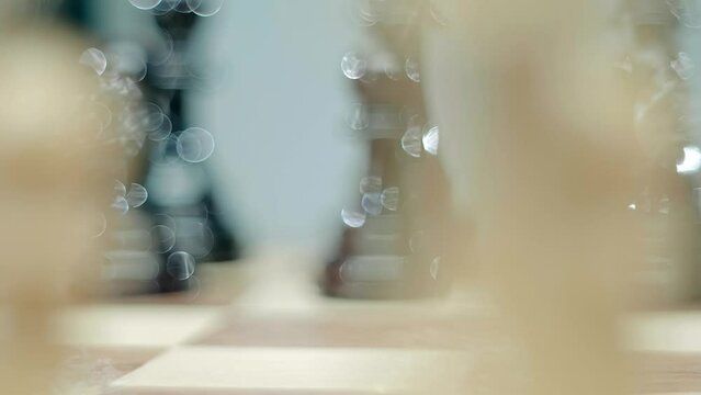 A woman's hand with beautiful blue nails with sparkles that glitter in the light moves a pawn on a chessboard during a chess competition. Closeup. Macro. Shallow depth of field. Shot in motion
