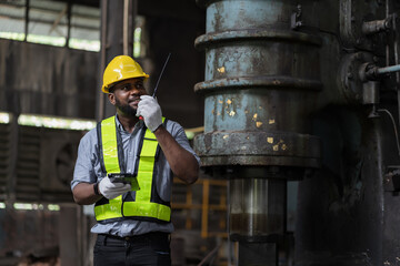 African American male engineer factory worker using radio communication in the industry factory...