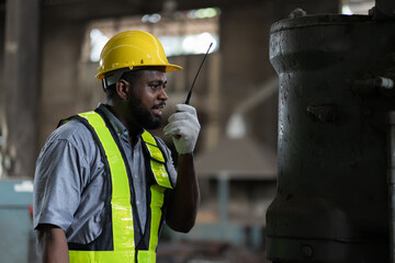 African American male engineer factory worker using radio communication in the industry factory...