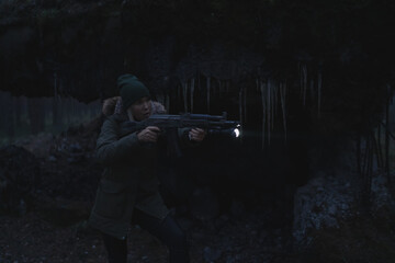 A civilian girl with a machine gun and a flashlight takes aim at night in the dark in the forest...