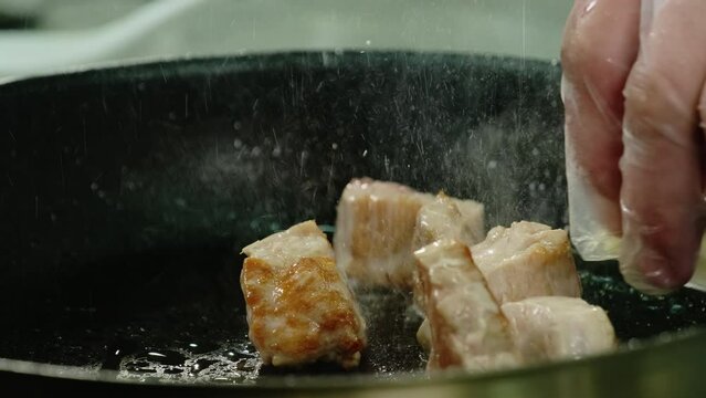 Cook carefully puts onion slices into pan where meat slices frying. Beef cubes soak flavors of onion and oil getting unique taste