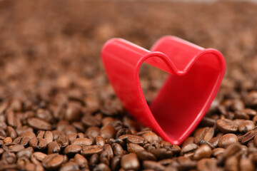 Fototapeta premium Red heart in roasted coffee beans background.