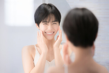 A beautiful woman looking in the mirror at a washbasin that is easy to use for beauty and other...