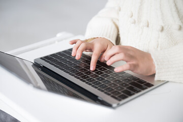パソコンのキーボードでタイピングする小学生の女の子の手元　顔なし