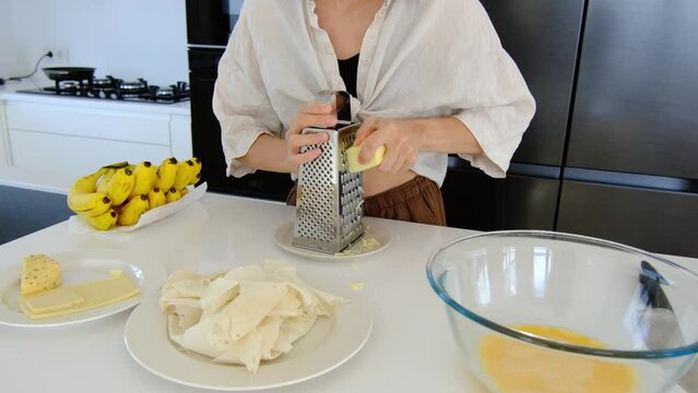woman in kitchen make dinner, young woman grates cheese to prepare delicious omelet with cheese.