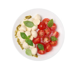 Plate of tasty Caprese salad with mozzarella, tomatoes, basil and pesto sauce isolated on white, top view