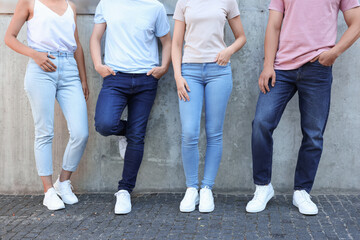 Naklejka premium Group of people in stylish jeans near grey wall outdoors, closeup