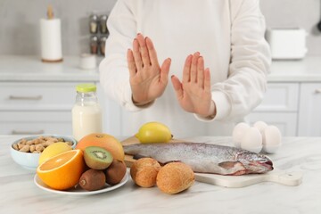 Woman suffering from food allergies refusing eat different fresh products at light table indoors,...