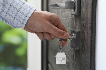 Man unlocking door with key outdoors, closeup