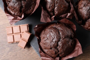 Tasty chocolate muffins on wooden table, top view