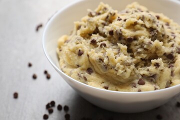 Chocolate chip cookie dough in bowl on light gray table, closeup